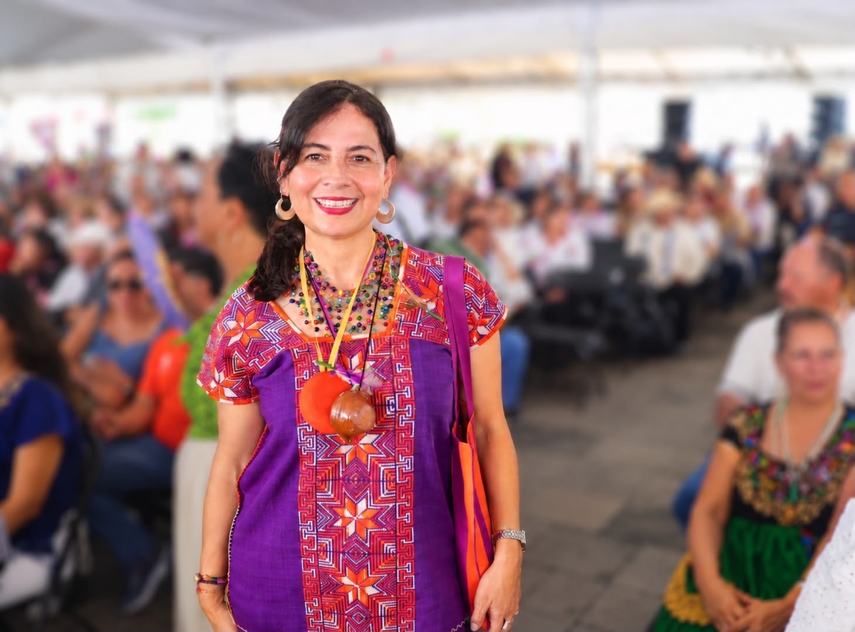 Mujer sonriente con vestimenta tradicional en evento de entrega de créditos Finabien en Apatzingán