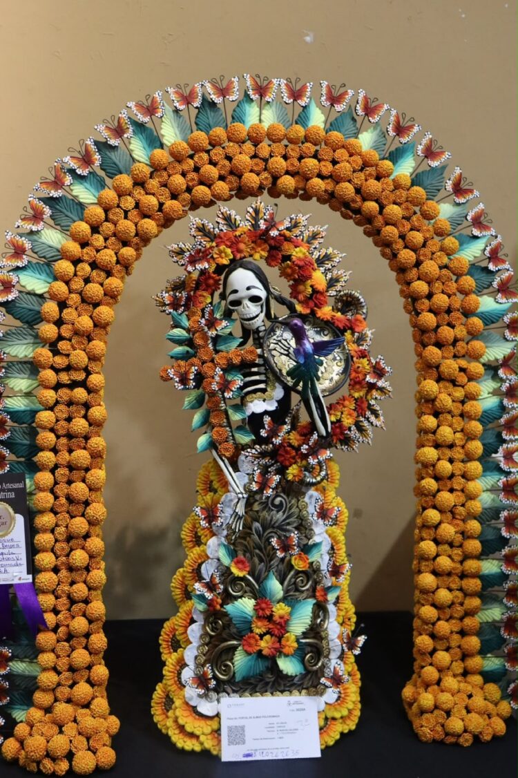 Un esqueleto decorado con flores y mariposas está bajo un arco floral colorido.