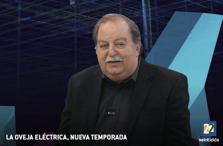 Un hombre de cabello canoso y bigote blanco, con saco negro, está frente a un fondo azul en un programa titulado “La Oveja Eléctrica, Nueva Temporada”.