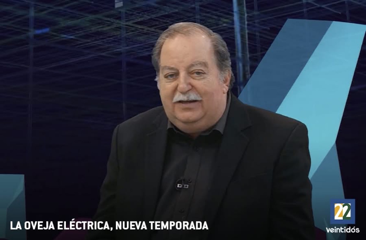 Un hombre de cabello canoso y bigote blanco, con saco negro, está frente a un fondo azul en un programa titulado “La Oveja Eléctrica, Nueva Temporada”.