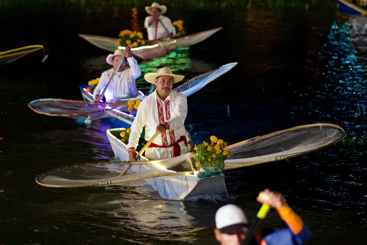 Canoas con flores de cempasúchil navegan de noche en los canales de Urandén durante la Noche de Muertos.