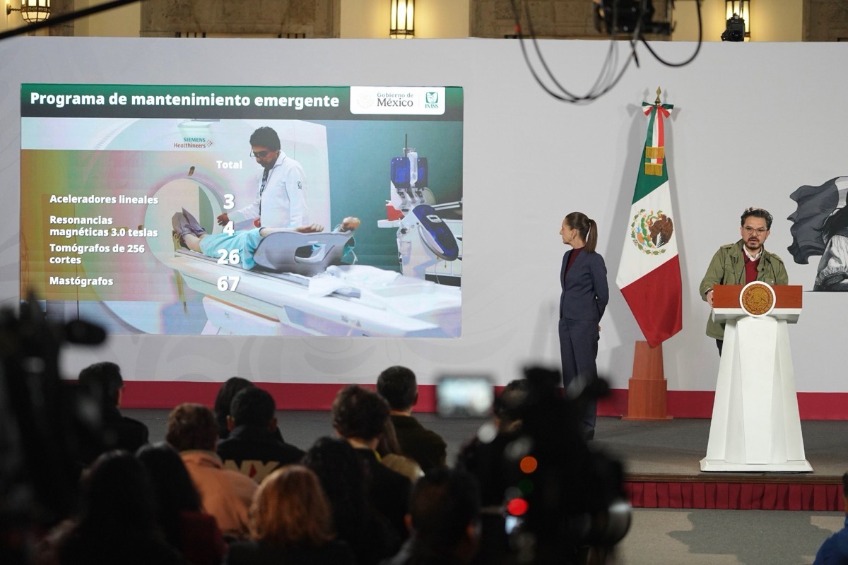 Escena de una conferencia con panel y pantalla mostrando gráficos sobre mantenimiento emergente y cifras, presencia de una ab.