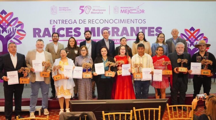 Un grupo de personas posa en un escenario sosteniendo trofeos y certificados durante una ceremonia de reconocimiento.